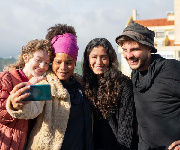 A diverse group of people in a bright yoga class, smiling and holding a pose.