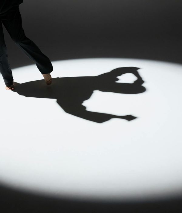 Woman performing a fluid, dynamic yoga pose in a dark studio with purple light.